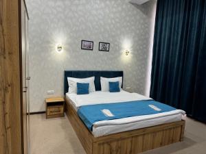 ein Schlafzimmer mit einem großen Bett mit blauer Bettwäsche und Kissen in der Unterkunft Cobbler by Resident in Taschkent