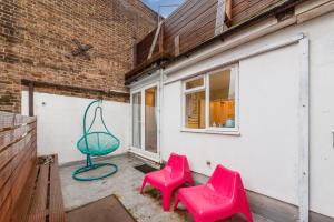 a pair of pink chairs sitting next to a building at Modernised Apartments 1 and 2 Bedrooms Option Terrace and Balcony High Street in London
