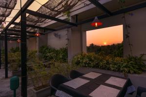 un patio con una mesa y una puesta de sol en el fondo en Hotel Riveria by Raj en Mūvattupula