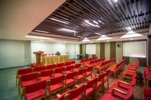 una sala de conferencias con sillas rojas y un podio en Hotel Riveria by Raj en Mūvattupula