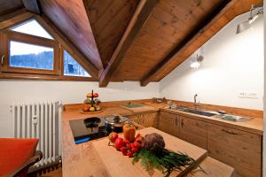 a kitchen with wooden cabinets and a table with vegetables on it at Appartamento La Fontaine Ski In Ski Out - Happy Rentals in Claviere