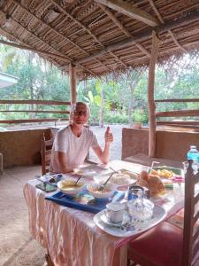 a man sitting at a table with a plate of food at Nirwana Resort in Habarana