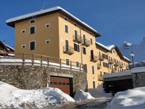 a large building with a garage in the snow at Le Cherillon Apartment in Breuil-Cervinia