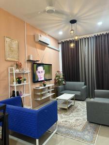 a living room with blue couches and a flat screen tv at Homestay Afeef Jerantut in Jerantut