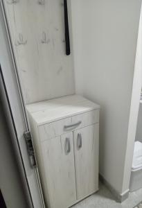 une petite armoire blanche dans une salle de bains à côté des toilettes dans l'établissement Jugi, à Novi Pazar