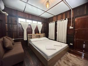 1 dormitorio con cama y sofá en ม่วนใจ๋ปันสุข โฮมสเตย์แอนคาเฟ่ Muanjai punsuk homestay and cafe, 