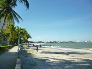 a beach with palm trees and people on it at Glory Beach Resort in Port Dickson