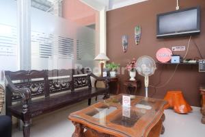 uma sala de estar com um banco e uma mesa em Travelista Homestay near GOR Candradimuka Semarang Mitra RedDoorz em Srondolwetan