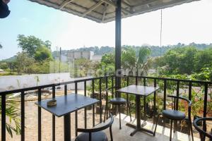 a balcony with tables and chairs and a view at Travelista Homestay near GOR Candradimuka Semarang Mitra RedDoorz in Srondolwetan
