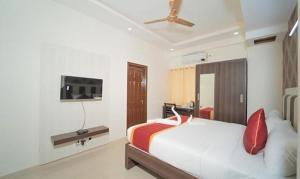 a bedroom with a bed and a tv on the wall at FabHotel Panchami Comforts in Bangalore