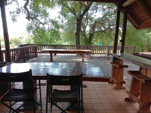 a table and chairs on a deck with a bench at Hoedspruit River Lodge in Hoedspruit