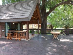 un pabellón de madera con mesas de picnic y un árbol en Hoedspruit River Lodge, en Hoedspruit