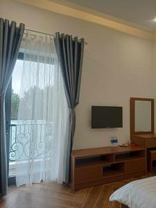 una camera con un letto e una finestra con televisore di Khách sạn Mimosa a Kon Plong