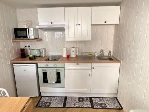 una cucina con armadi bianchi, piano cottura e lavandino di L'atelier des rêves a Kaysersberg