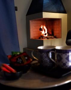 a fireplace with two tea cups on a table at PODERE DELL'ETNA SEGRETA - Essential Nature Hotel in Biancavilla