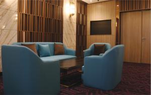 a waiting room with two blue chairs and a television at Aqueen Prestige Hotel Lavender in Singapore