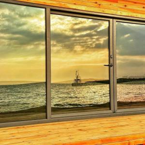 une fenêtre avec vue sur l'océan et un bateau dans l'établissement BEACH HOUSES, à Tuzla
