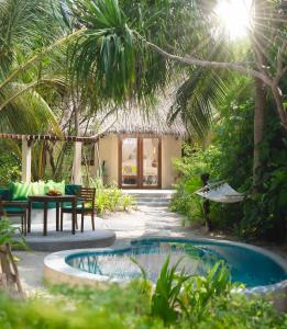 ein Resort mit einem Pool, einem Tisch und Stühlen in der Unterkunft Coco Palm Dhuni Kolhu in Thulhaadhoo