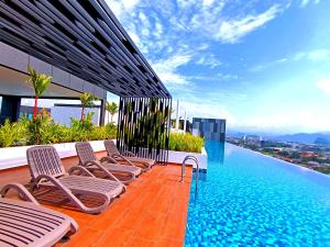 a pool on the roof of a building with chairs at The Horizon Ipoh 2BR L11 by Grab A Stay in Ipoh