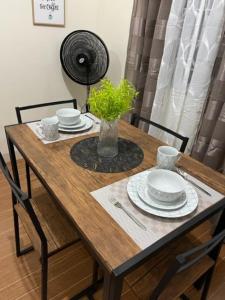 Estilo 2-Bedroom Apartment B في Loculan: طاولة خشبية عليها صحون ونبات