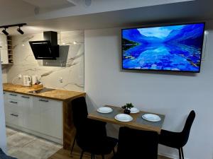 a kitchen with a table and a tv on the wall at Apartament Szafran ApartamentyZakopianskie Basen Sauna Jacuzzi in Zakopane