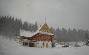 a large wooden house with snow on the roof at Fifth Element Retreat in Borzont