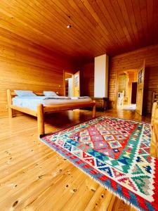 1 dormitorio con cama y alfombra en el suelo de madera en Fifth Element Retreat, en Borzont