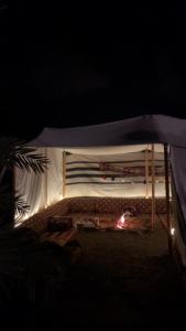 a white tent with a fire under it at night at Mountain house in AlUla