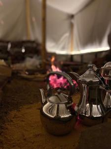 two silver teapots sitting on top of a table at Mountain house in Al-ʿUla