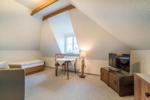 a attic room with a bed and a television at Pension Wosmaaren in Norddorf