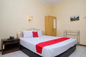 una camera da letto con un grande letto bianco con una coperta rossa di RedDoorz Plus @ Laweyan a Solo
