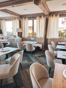 um restaurante com mesas, cadeiras e janelas em Chalet Hotel Le Mont Bisanne em Crest-Voland