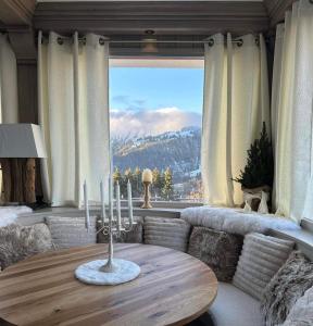 - un salon avec une table et une grande fenêtre dans l'établissement Chalet Hotel Le Mont Bisanne, à Crest-Voland