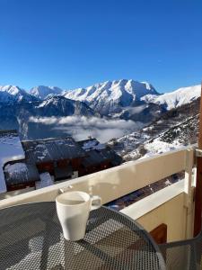 d'un balcon avec une table et une vue sur les montagnes enneigées. dans l'établissement Sunny studio Mountain View balcony Alpe d Huez Studio ensoleillé balcon vue montagne, à L'Alpe-d'Huez
