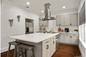 una cocina con armarios blancos y una gran isla blanca en Experience Serenity in a 4BR3BA Downtown Home, en San Antonio