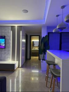 una cocina con iluminación púrpura y un bar con taburetes en Appartement La Croisette en Nabeul