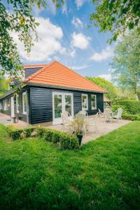 een zwart huis met stoelen en tafels ervoor bij B&B de Luwte Cottage in Zwolle