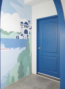 une porte bleue dans une pièce ornée d'une peinture représentant une maison dans l'établissement Now Hostel, à Ban Chang