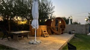 an umbrella on a patio with a table and a tent at Casa Anastasia in Murighiol