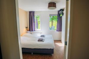a bedroom with a bed and a window at B&B de Luwte Cottage in Zwolle
