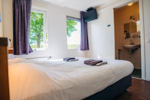 Bett in einem Zimmer mit Fenster und Waschbecken in der Unterkunft B&B de Luwte Cottage in Zwolle