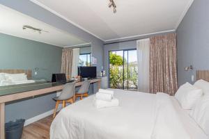 a bedroom with a bed and a desk with a computer at Bloubergstrandlodge in Bloubergstrand