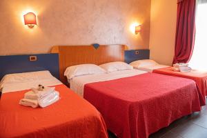 two beds in a hotel room with red and white sheets at Hotel Bellavista in Marina di Varcaturo