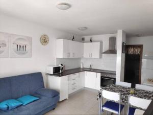 a living room with a blue couch and a kitchen at Apartamento Happyness Complex Amaya Fuerteventura in Costa de Antigua