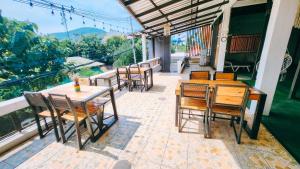 Downtown Kohlarn Resort في كو لان: فناء به طاولات وكراسي خشبية على شرفة