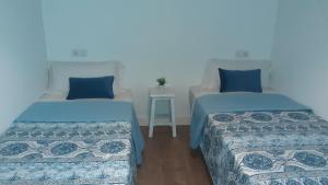 two beds in a room with blue pillows at Hospédate Pontevedra in Pontevedra