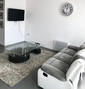 a living room with a couch and a clock on the wall at Maison entière proche circuit des 24 heures in Le Mans +10 photos