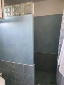 La salle de bains est pourvue d'une douche et d'un mur bleu. dans l'établissement AGERAKI, à Lipsi
