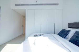 een slaapkamer met een groot wit bed met blauwe kussens bij Stunning 2BR with Sea and Ain Dubai View at JBR in Dubai