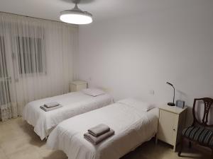 2 Betten in einem weißen Zimmer mit einem Stuhl in der Unterkunft MAND CANTERAS in Las Palmas de Gran Canaria